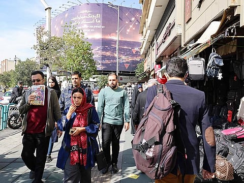 People walk along a street in Tehran on Saturday. Residents of Tehran awoke and went about their business as planned on October 26 after their sleep was troubled by Israeli strikes that triggered blasts that echoed across the city.