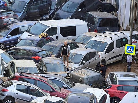 Persons climb on piled up cars following deadly floods in Sedavi, south of Valencia, eastern Spain, on October 30, 2024.