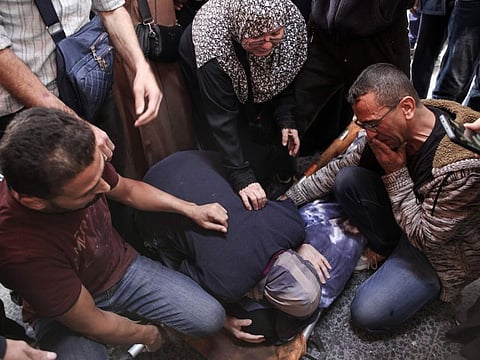 Relatives react over the shrouded body of a person killed in an Israeli strike that targeted areas in the northern Gaza Strip, outside the al-Maamadani hospital on October 31, 2024.