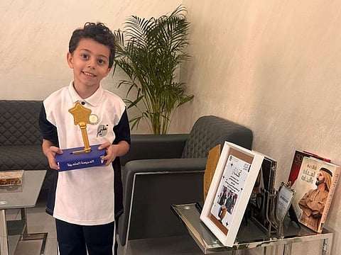 Grade 1 student Rayyan wears the badge while posing with the Best School Award of Arab Reading Challenge at his school, Al Ibda’a Model School-Cycle 1, recently