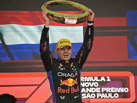 Red Bull Racing's Dutch driver Max Verstappen celebrates at the podium with the trophy of the Formula One Sao Paulo Grand Prix.