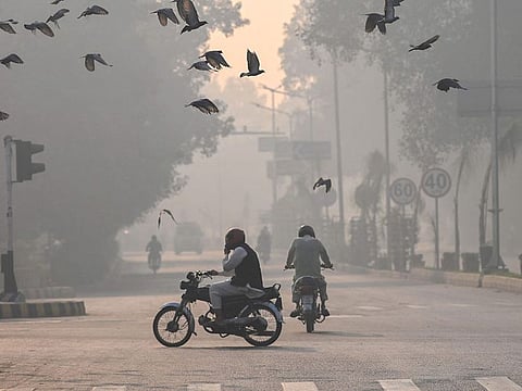Commuters make their way amid smog in Lahore on November 2, 2024.