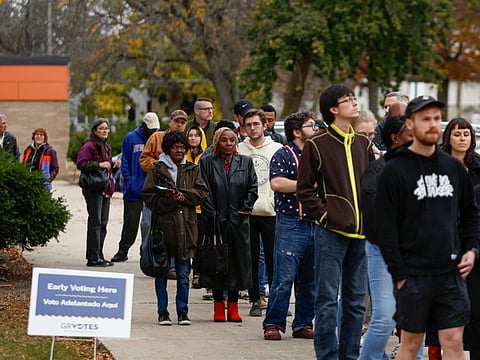 People wait in line to vote during early voting for the US general election at a polling station at Ottawa Hills High School in Grand Rapids, Michigan, on November 3, 2024.