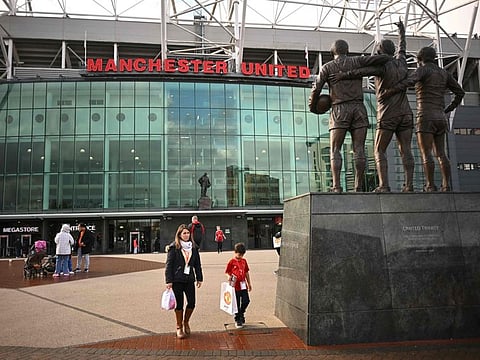 Visitors walk past Old Trafford in Manchester. The fans have voted for building a new stadium rather than redeveloping the existing one.