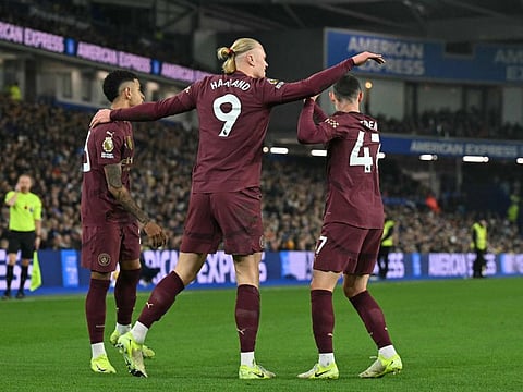 Manchester City's Norwegian striker Erling Haaland celebrates with midfielders Savinho (left) and Phil Foden (R) after scoring the opening goal of the English Premier League football match against Brighton at the American Express Community Stadium in Brighton, southern England on November 9.