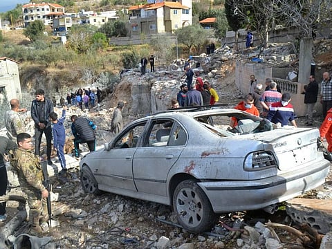 First responders search around a damaged car at the site of an overnight Israeli strike on Ain Yaacoub in Akkar on November 12, 2024.