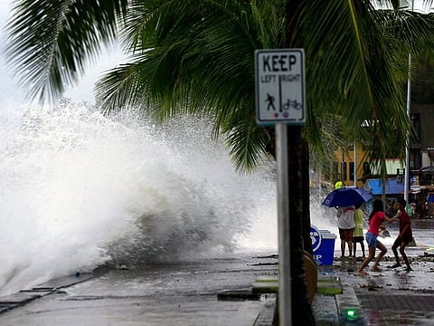 People (right) react as large waves break along a seawall ahead of the expected landfall of Super Typhoon Man-yi, in Legaspi City, Albay province on November 16, 2024.