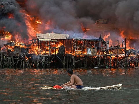 A man watches houses on fire at Tondo in Manila on November 24, 2024.