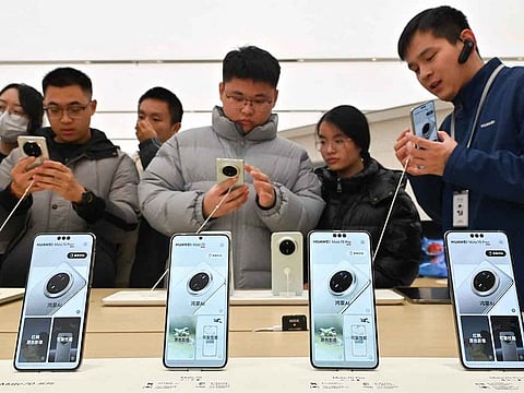 People check Huawei's new Mate 70 mobile phone inside a shop at the Wangfujing shopping area in Beijing on November 26, 2024.