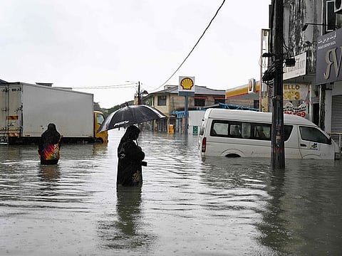 A woman looks at a submerged vehicle during heavy rain in Pasir Puteh, in Malaysia's Kelantan state on November 30, 2024.