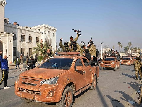 Syrian anti government fighters celebrate as they pour into the captured central-west city of Hama on December 6, 2024.