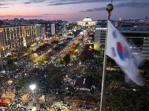 A South Korea flag flutters in the wind as a general view shows people taking part in a protest calling for the ouster of South Korea President Yoon Suk Yeol outside the National Assembly in Seoul.