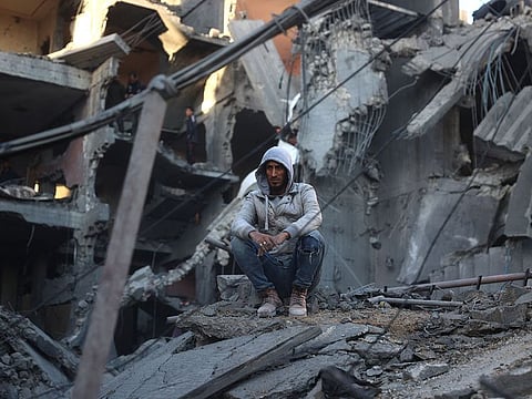 A Palestinian man sits on the rubble of a destroyed building in the Nuseirat refugee in the central Gaza Strip