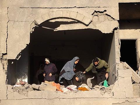 People look for salvageable items following an Israeli strike in Deir Al Balah in the central Gaza Strip on December 22, 2024.
