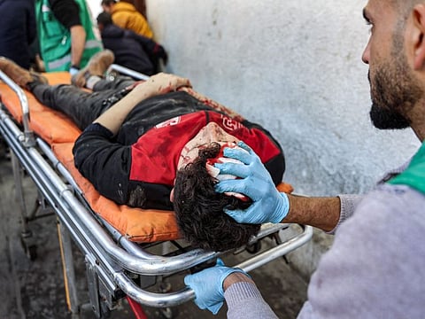 Palestinian Red Crescent paramedics transport on a gurney a person who was injured in a reported strike on a Palestinian civilian vehicle by Israeli forces, after arriving for medical care at the Ahli Arab Hospital in Gaza City on December 22, 2024.