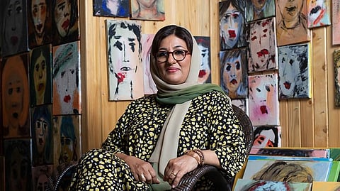 Nujoom Al Ghanem at her studio, whose walls are covered by paintings of faces