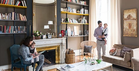The muted tones of the living room create a cosy atmosphere around the fireplace, while the coloured shelves and reflective surfaces, such as the copper pendant light by Tom Dixon, give it a modern lift