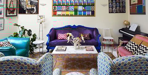 The living room is a riot of colour with mismatched pre-loved sofas given a new life with a splash of paint.
