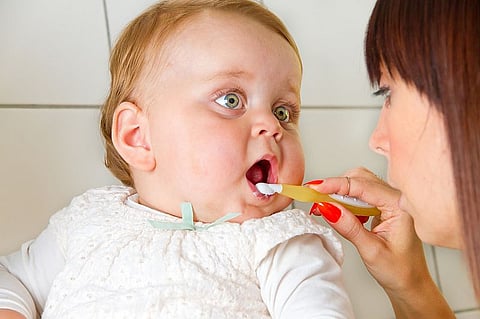 mother brushing baby\'s teeth
