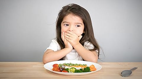 a girl at the table with her mouth covered