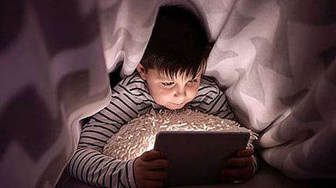 a boy in a bed with his ipad