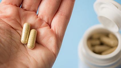 a person holding two pills on the hand