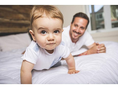 baby crawling with an adult in the backgound