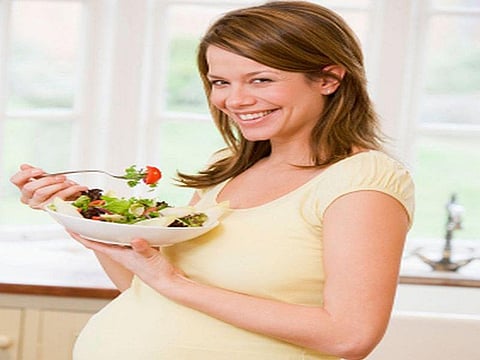 pregnant woman eating salad