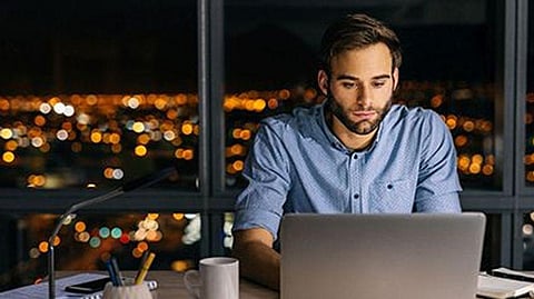 a man sitting at the computer late at night