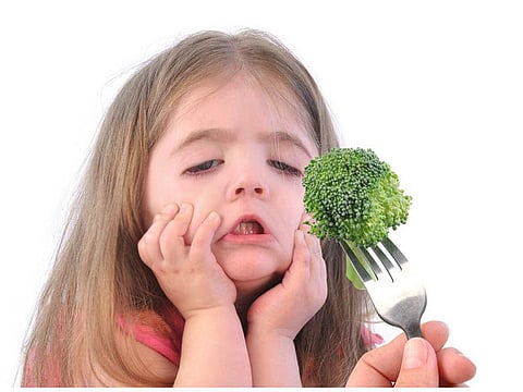 unhappy girl that doesn't want to eat broccoli