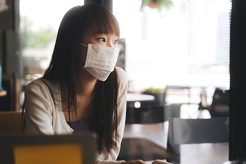 Young adult asian student female with face mask for virus corona or covid 19 study at cafe.