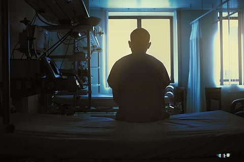 Figure of sitting patient on a hospital bed on the background of bright lights