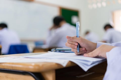 Asian Student girls wear face mask prevent COVID-19 coronavirus in Classroom for final test education exam room on High school. Students hold pencil writing paper documents for taking exams in room