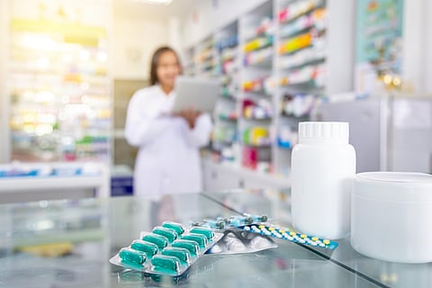 Capsules medicine and white medicine bottles on table in drugstore with blurred background of pharmacist and pharmacy.