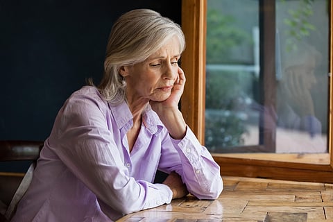 Sad senior woman sitting at table depression depressed