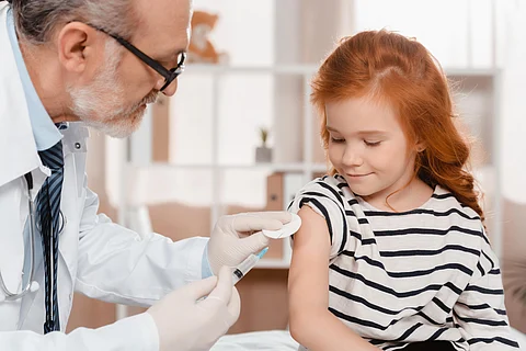 doctor in medical gloves making injection to little girl in clinic vaccine child