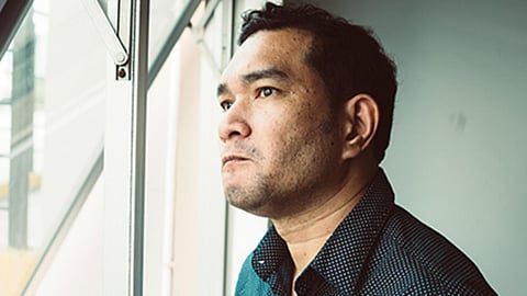 man looking out window vaguely frustrated