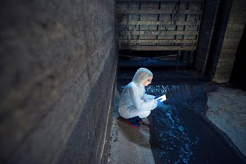 Ecologist expert taking water samples to examine pollution and contamination of waste water coming out of city sewage to the river. Water examination.