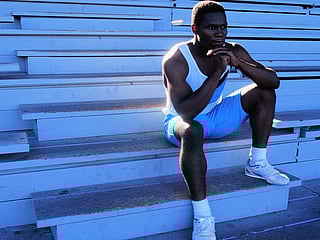 Black man sitting on bleachers after running