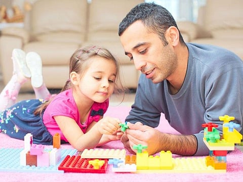 daughter and father playing with legos on the floor