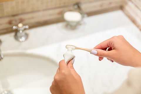 woman putting toothpaste on a toothbrush