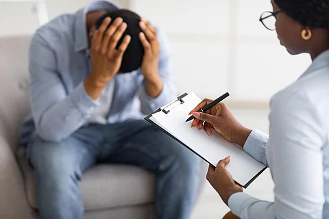 Concepto de psicoterapia. Hombre negro deprimido sosteniendo su cabeza en la oficina del consejero, buscando ayuda profesional con un trastorno mental. Psicólogo profesional teniendo sesión con paciente masculino desesperado
