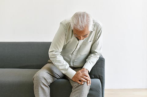 Problema de dolor articular de artritis en un anciano, hombre asiático anciano con gesto de mano en la rodilla, sufrimiento de la tercera edad y preocupación por el síntoma de la lesión, concepto de seguro de salud.