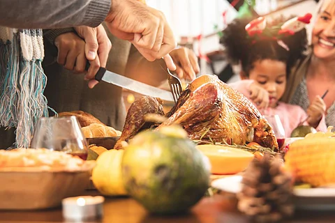 Thanksgiving Celebration Tradition Family Dinner Concept.family having holiday dinner and cutting turkey.Young black adult woman and her daughter happy.