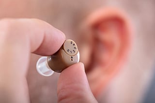 Close-up Of A Man's Hand Putting Hearing Aid In His Ear