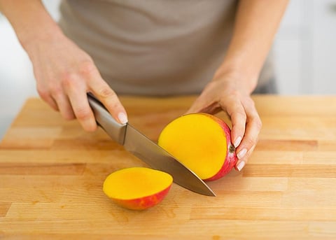 Primer plano de una mujer cortando mango
