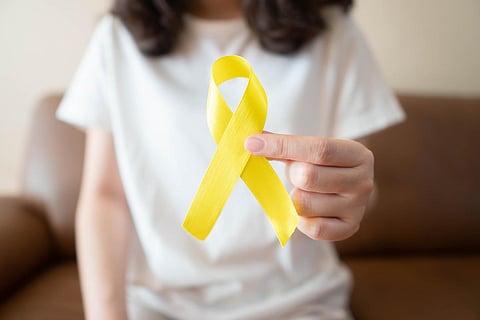 Young female holding yellow gold ribbon awareness symbol for suicide prevention