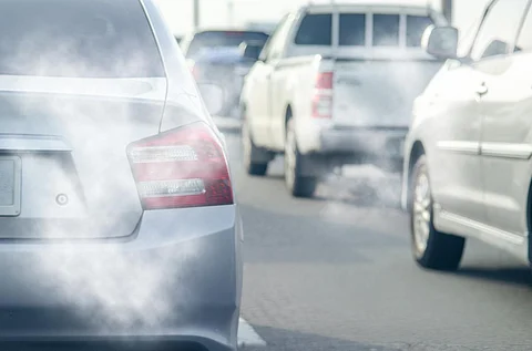 Humo del tubo de escape del coche en la carretera