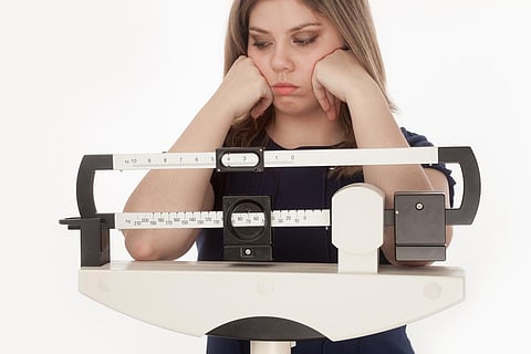 Young woman dissapointed on a medical weight scale.