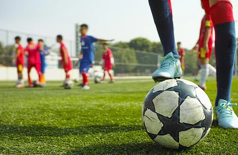 grupo de niños asiáticos jugando al fútbol por la mañana
